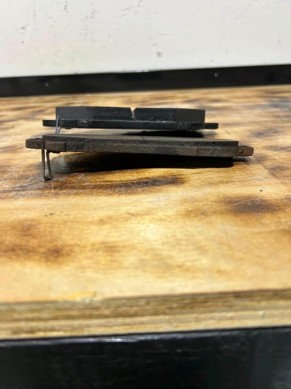 An old brake pad beside its new replacement